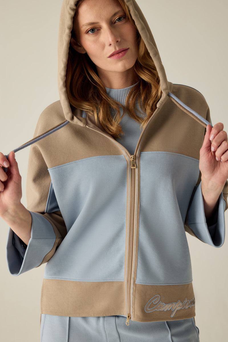 Hochwertige Damen-Sweatshirtjacke mit Kapuze und Doppel-Kordel, modernem Materialmix in Caramel & Blau und überschnittenen Schultern. Der verlängerte Rücken sorgt für eine lässige Silhouette, während die Pailletten-Stickerei am Saum edle Akzente setzt...